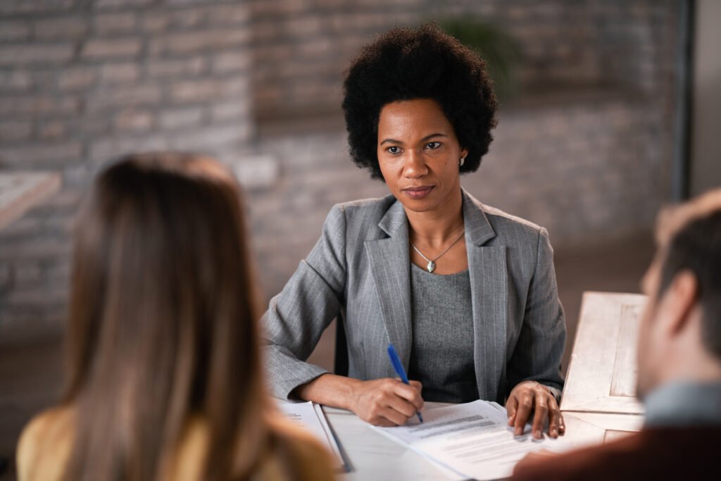 Black female financial planner taking notes while having a meeting with her clients.